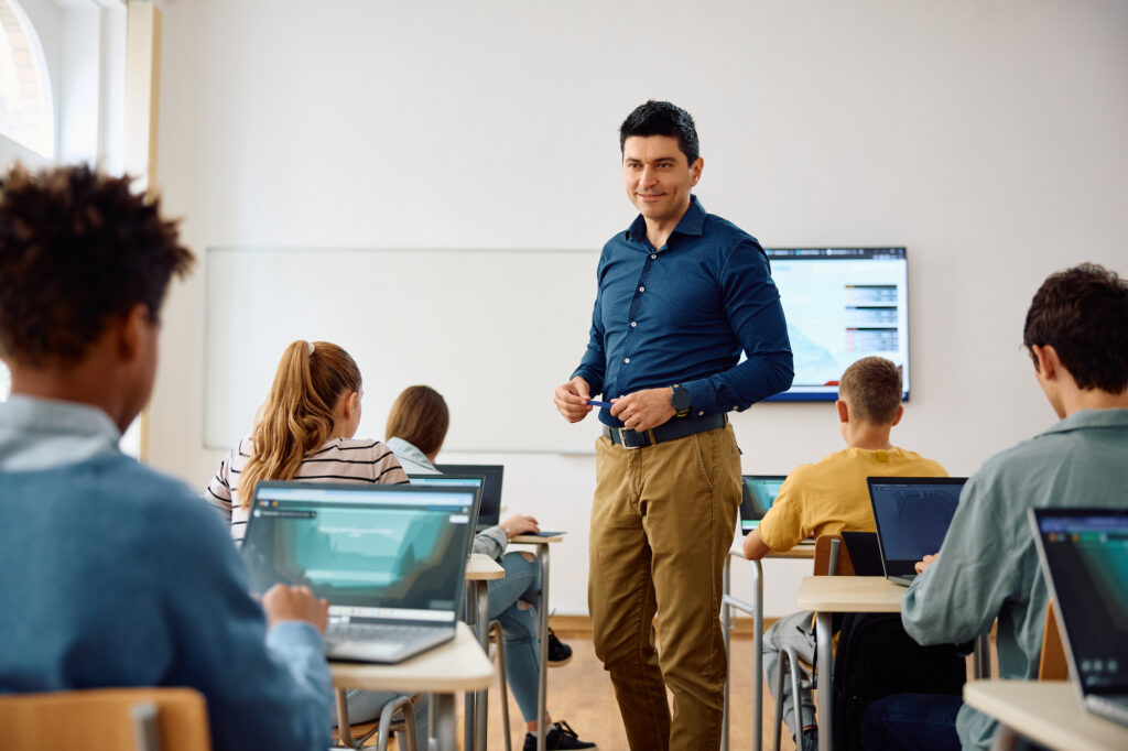 Computer science teacher and high school students having a class in the classroom overcoming the challenges of online learning.