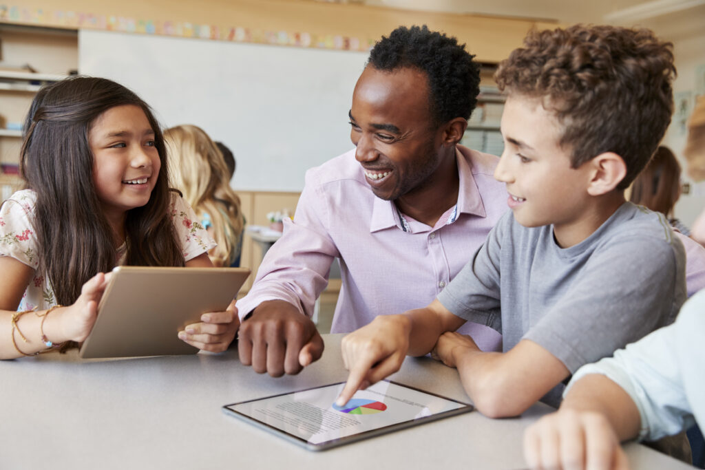 Teacher helping school kids using tablet computers in lesson